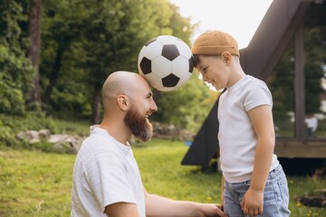Father and son playing with soccer ball celebrating Father's Day