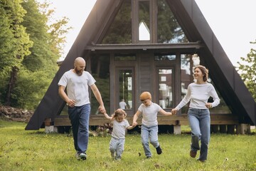 Happy family running together in front of their modern a frame house