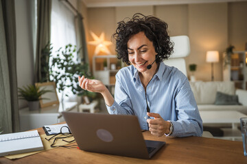 call center female agent wearing headset talk to client at home office