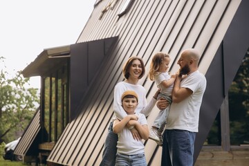 Happy family posing in front of their modern house