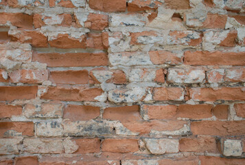 Close-up full-frame old brick wall with red and white weathered bricks and exposed mortar. Rustic, chipped surface, age and decay. Textured background or architectural detail, wallpaper. Urban vintage