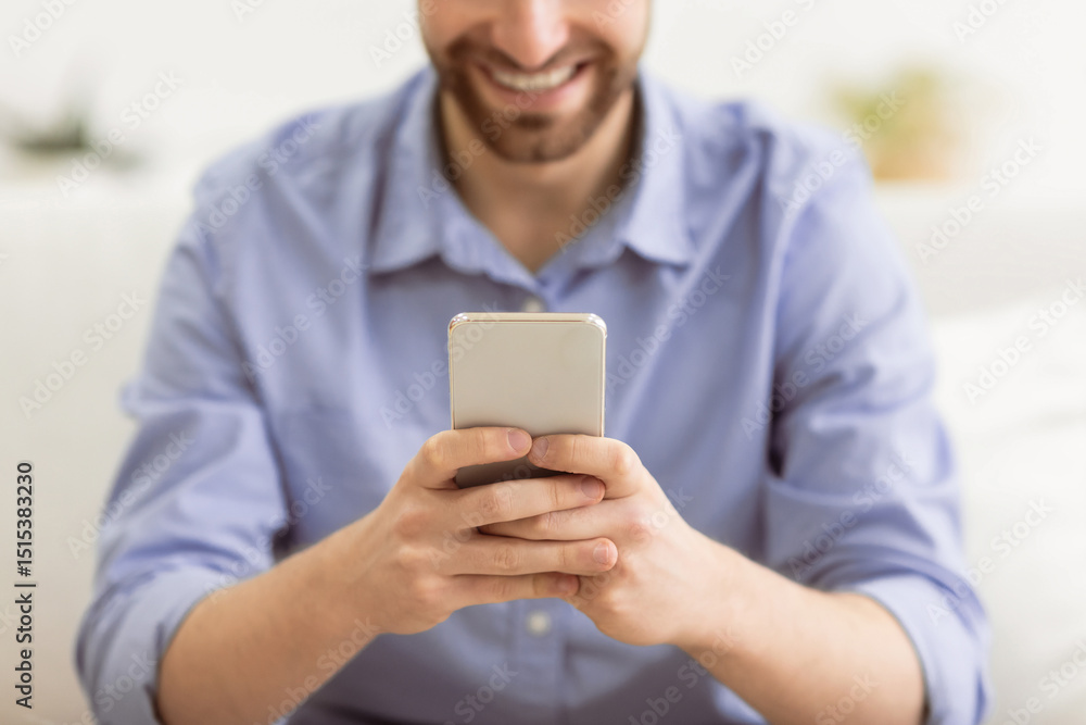 Aufkleber happy bearded guy using smartphone texting and using mobile application on phone sitting on couch at