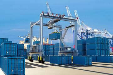 Automated crane lifting blue shipping containers at a modern seaport terminal with cargo ships and logistics infrastructure. – Shipping, Logistics, Customs