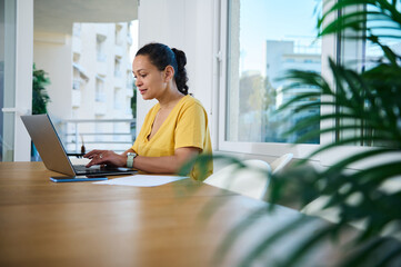 Focused Woman Working on a Laptop in a Modern Home Office Environment