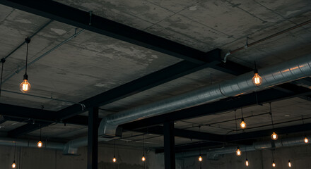 An open ceiling with exposed concrete, ductwork, black steel beams, and vintage filament bulbs hanging on cords.