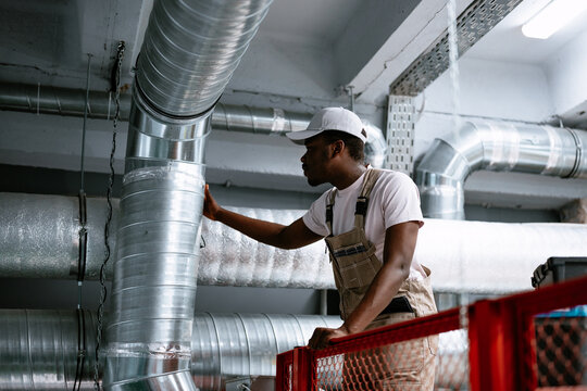 Skilled worker inspecting air ducts in a commercial building during the daytime