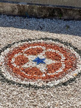 Pebble mosaic mandala with colorful gravel in a garden path