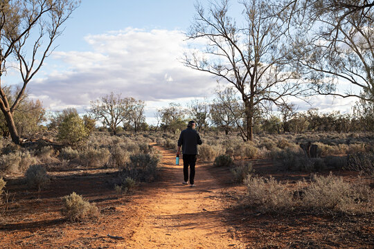 Middle aged man walking alone along a path in the outdoors and nature of outback of New South Wales, Australia. 
