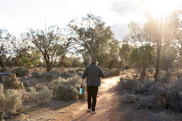 Middle aged man walking alone along a path in the outdoors and nature of outback of New South Wales, Australia. 