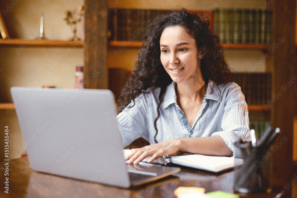Poster doing project. portrait of curly young woman using laptop computer and typing on keyboard, writer si