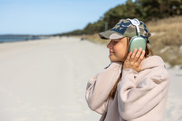 Girl listening to music in headphones on the seashore. Outdoor walk. Outdoor relaxation.