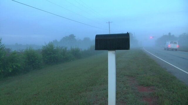 Pan of mailbox on the side of the road in moring mist 