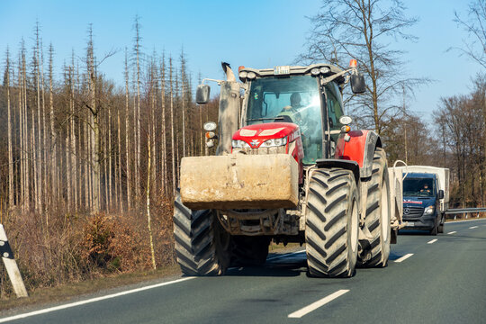 tractor at a small street carrying a big sandstone rock and cars at tze street can't overtake