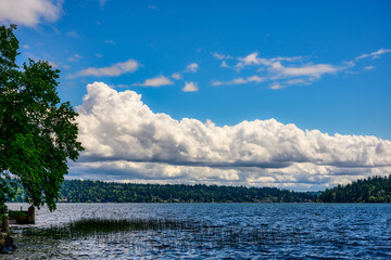 2025-05-28 A VIEW OF LAKE WASHINGTON FROM THE SOUTH END OF MERCER ISLAND WITH A CALM LAKE AND A CLOUDY SKY NEAR SEATTLE WASHINGTON