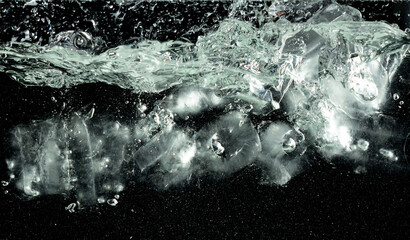 Falling ice tube pieces with water splashing in midair on a transparent, isolated black background. Ice tubes drop into water with air bubbles scatter splashing