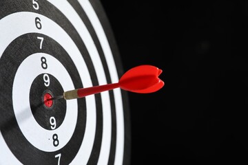 Targeting. Dart board with arrow on black background, closeup