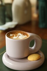 Aromatic coffee in cup and cookie on table, closeup