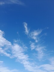 Bright blue sky with scattered fluffy clouds, creating a light and airy scene perfect for a calm,...