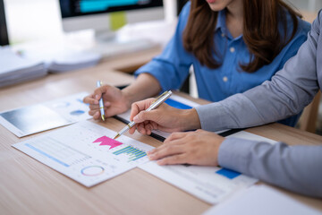 Two people are working on a project together, one of them is writing with a pen