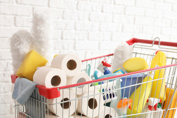 Shopping cart full of cleaning supplies near brick wall