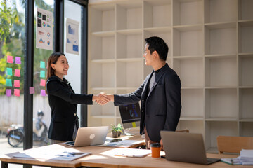 A man shakes hands with a woman in a business meeting
