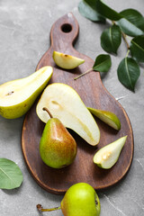 Wooden board with ripe pears on grey table, closeup