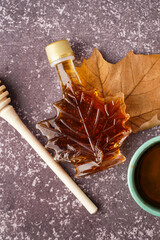 Bottle of tasty maple syrup on grey background