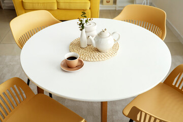 Dinning table with teapot and cup of coffee in room