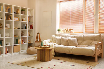 Interior of light living room with cozy sofa, wooden coffee table and bookshelves