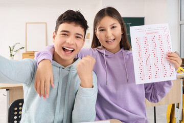 Happy teenage students with results of school test taking selfie in classroom