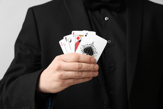 Young man with playing cards for poker on grey background, closeup