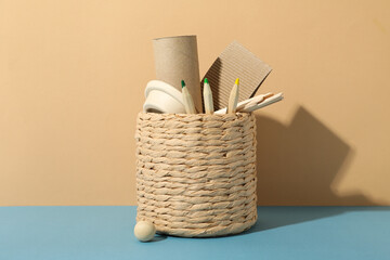 Handmade basket with paper things and pencils on beige background