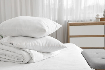 Cozy bed with folded blanket and stack of soft pillows in stylish bedroom, closeup