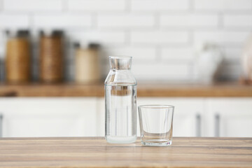 Glass and bottle of water on wooden table in kitchen