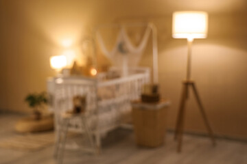 Interior of children's bedroom with crib, commode, glowing lamps and toys on baby chair at evening