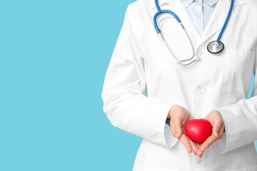 Female cardiologist with stethoscope and red heart on blue background, closeup