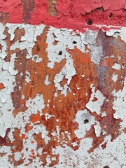 red paint on a wall, Painted cement wall, located outdoors, has chipped and peeling paint.