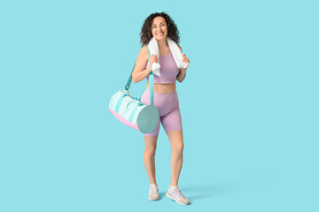 Fototapeta premium Mature woman with towel and sports bag on blue background