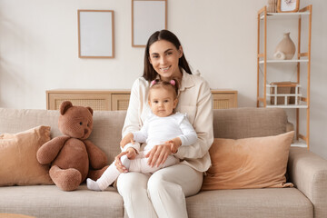 Mother with her baby sitting on sofa at home