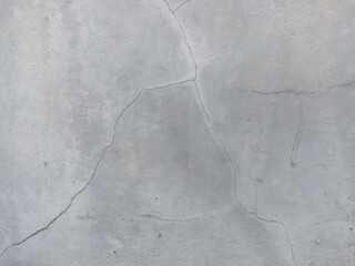 Cracked Concrete Surface. A close-up view of a gray concrete surface with prominent cracks, showcasing a worn and textured background