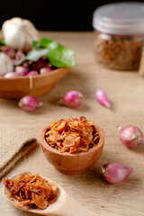 Bawang Goreng or Fried red onions in a wooden bowl. Crispy onion fries or shallots are fried to a golden brown color. Crispy fried onions. 