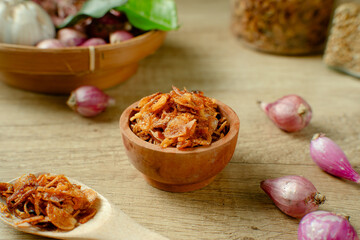 Bawang Goreng or Fried red onions in a wooden bowl. Crispy onion fries or shallots are fried to a golden brown color. Crispy fried onions. 