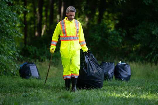 Volunteer in rubber gloves with trash bag clean up garbage on forest outdoor. Eco, environment conservation. Recycle pollution. Man collecting garbage and plastic trash. Save environment.