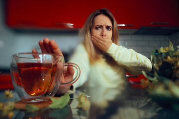 Woman Feeling Nauseated Refusing Tea She Does Not Like. Person disliking the bitter taste of a herbal beverage remedy
