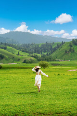 Young woman traveler relaxing and enjoying beautiful Scenery landscape with flowers in Nalati grassland of Xinjiang in summer