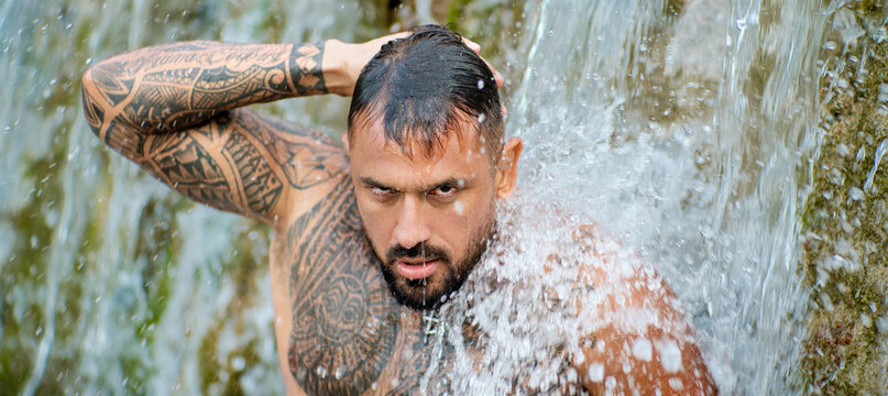 Sexy male body. Shirtless man splashing under waterfall. Fit and strong body. Handsome model enjoying summer water. Athletic male body. Man beauty on nature. Muscular body with water drops.
