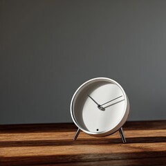 Minimalist white clock with thin silver legs sits on a wood surface, sunlit