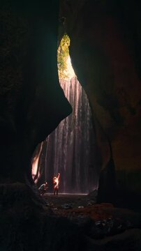 Silhouette Couple in love explore famous Bali travel destination Waterfall Tukad Cepung Bali, Indonesia 4K vertical video