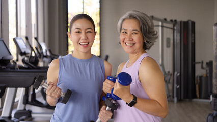 Young adult child and middle age old mum smile look at camera gym workout body weight picking up...