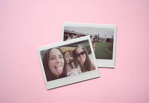 Two empty polaroid frames placed on a pink backdrop.